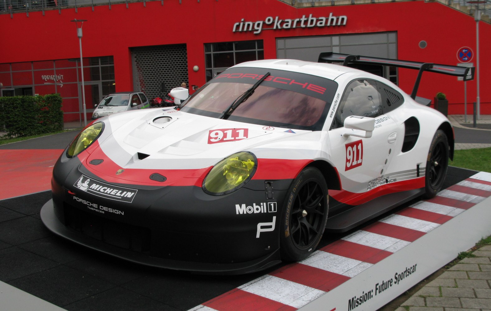Aerodynamic race car front and side with yellow headlights and large rear wing