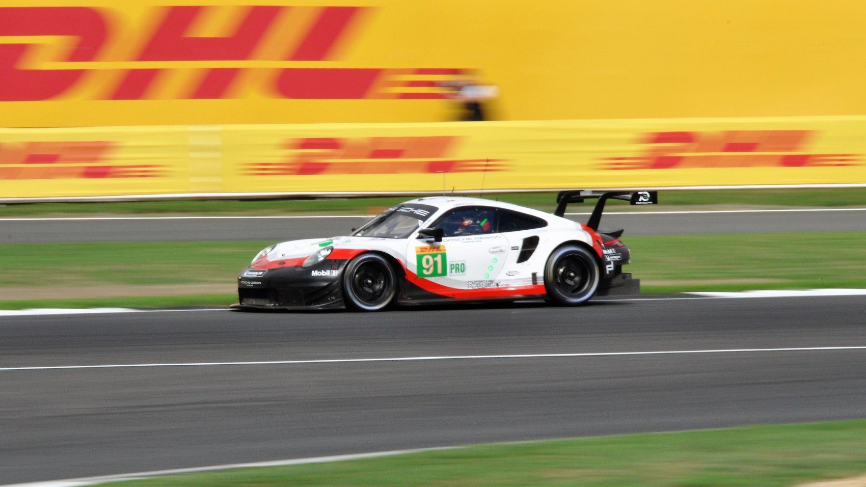 Race car with large rear wing and racing decals in side view.