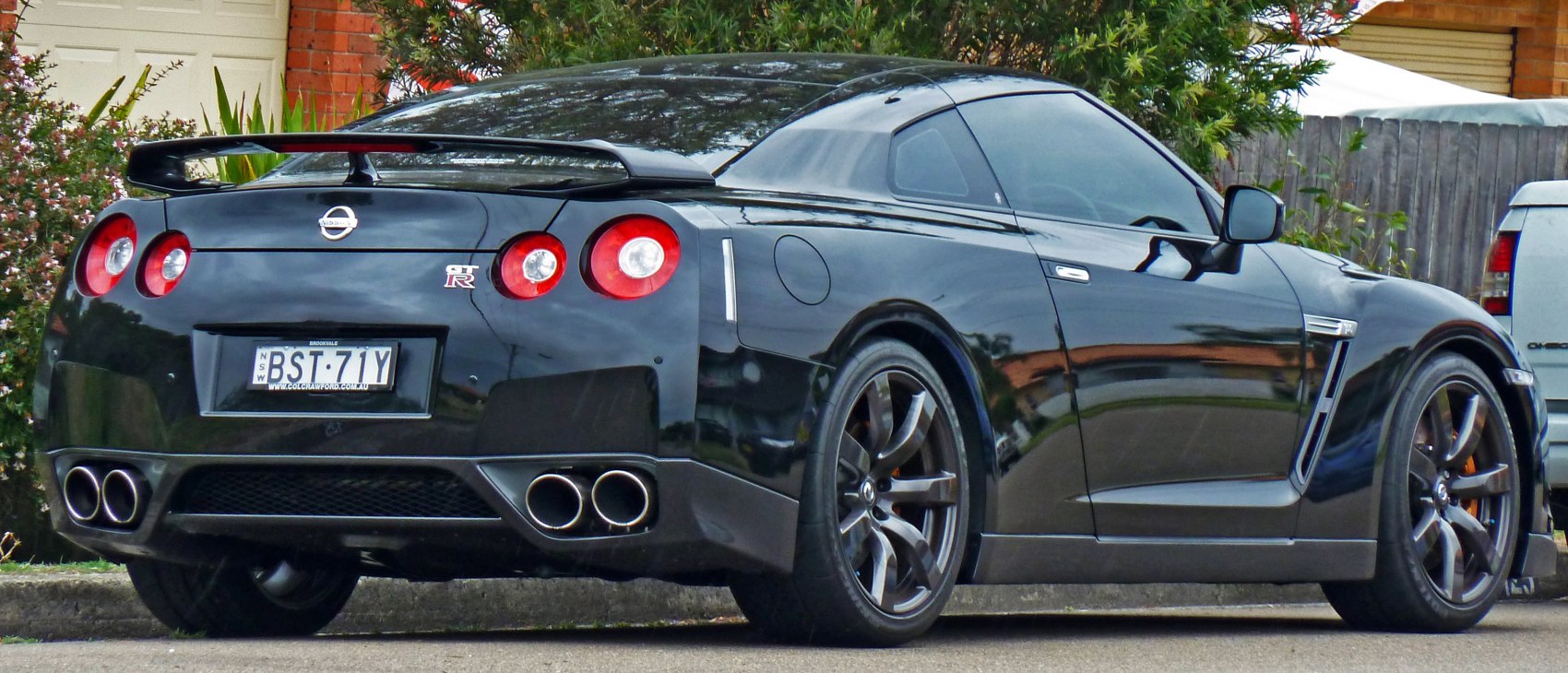 Rear spoiler, quad exhaust tips, round taillights on black coupe