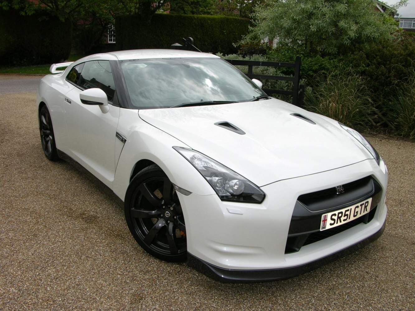 White sports coupe with black wheels and hood vents