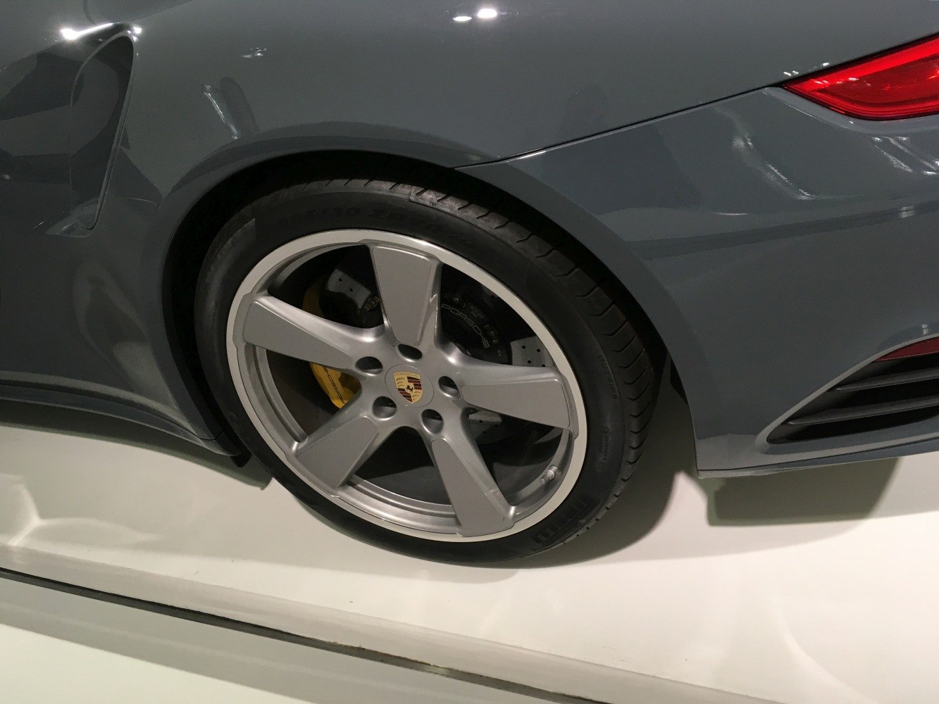 Rear alloy wheel with yellow brake caliper and perforated brake disc