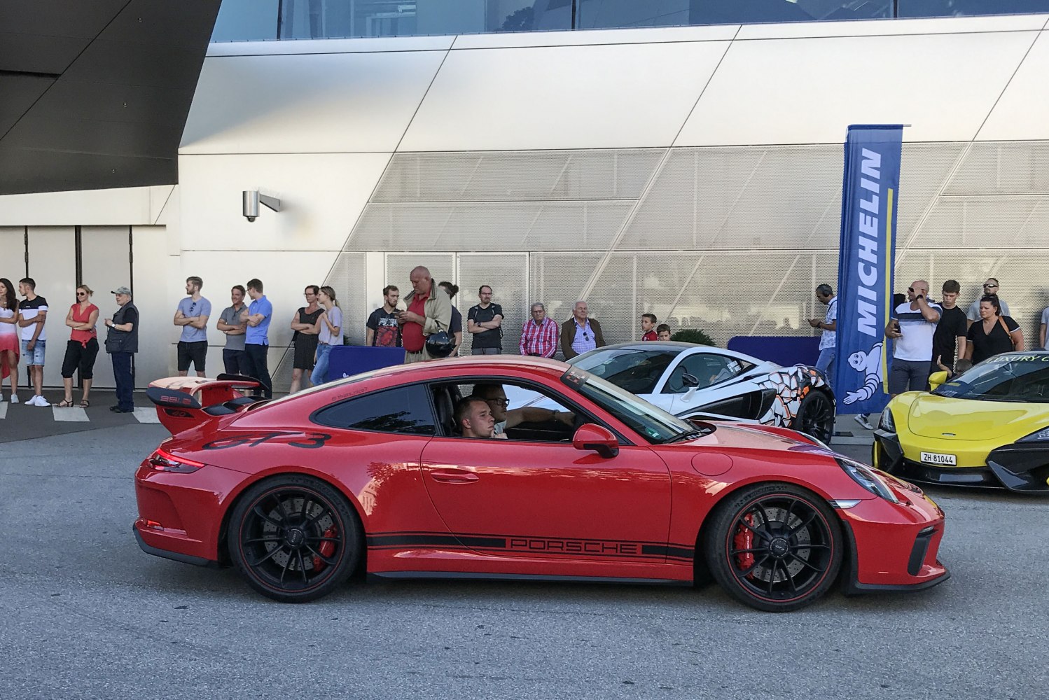 Red sports coupe with rear wing, black wheels, and side decals