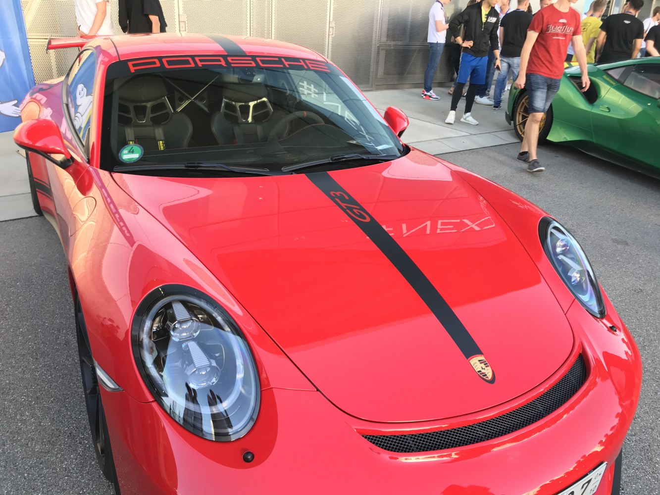 Red sports car front with black racing stripe and clear headlights
