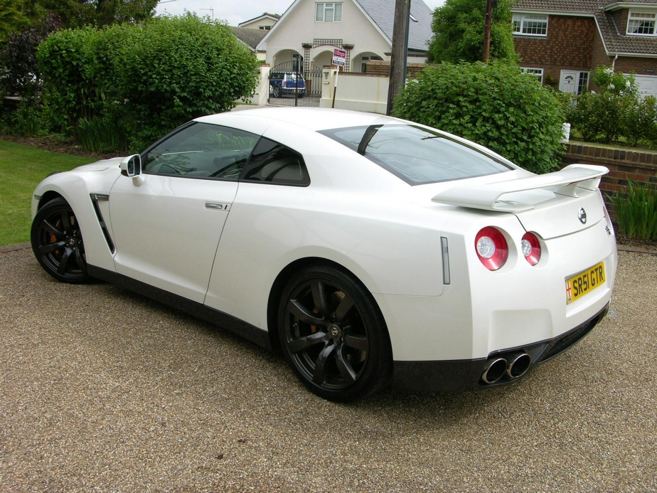 Rear side view of a sports coupe with spoiler and quad exhaust