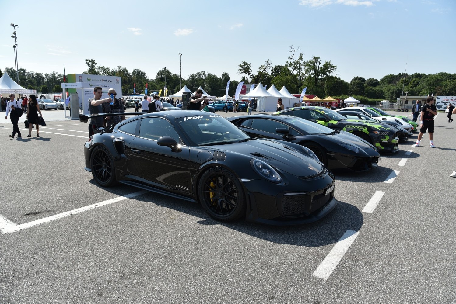 Black Porsche 911 GT2 RS with large rear wing parked among sports cars