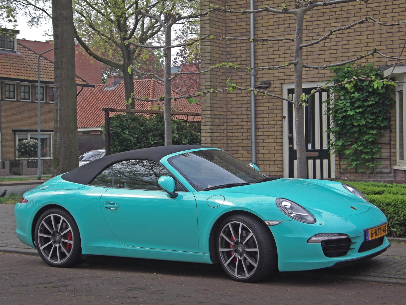 Teal sports convertible with black soft top roof and alloy wheels