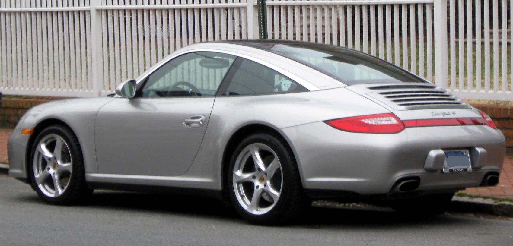 Silver sports car rear side with Targa roof and distinctive rear lights