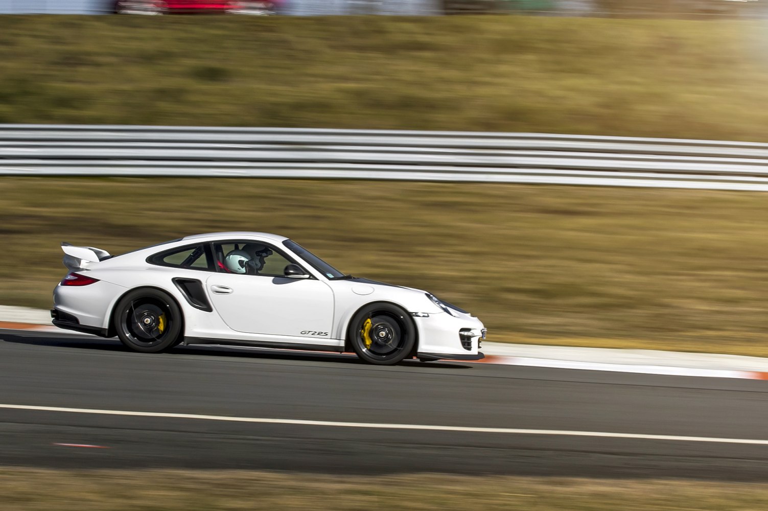 White Porsche 911 GT2 RS racing on track with aerodynamic wing