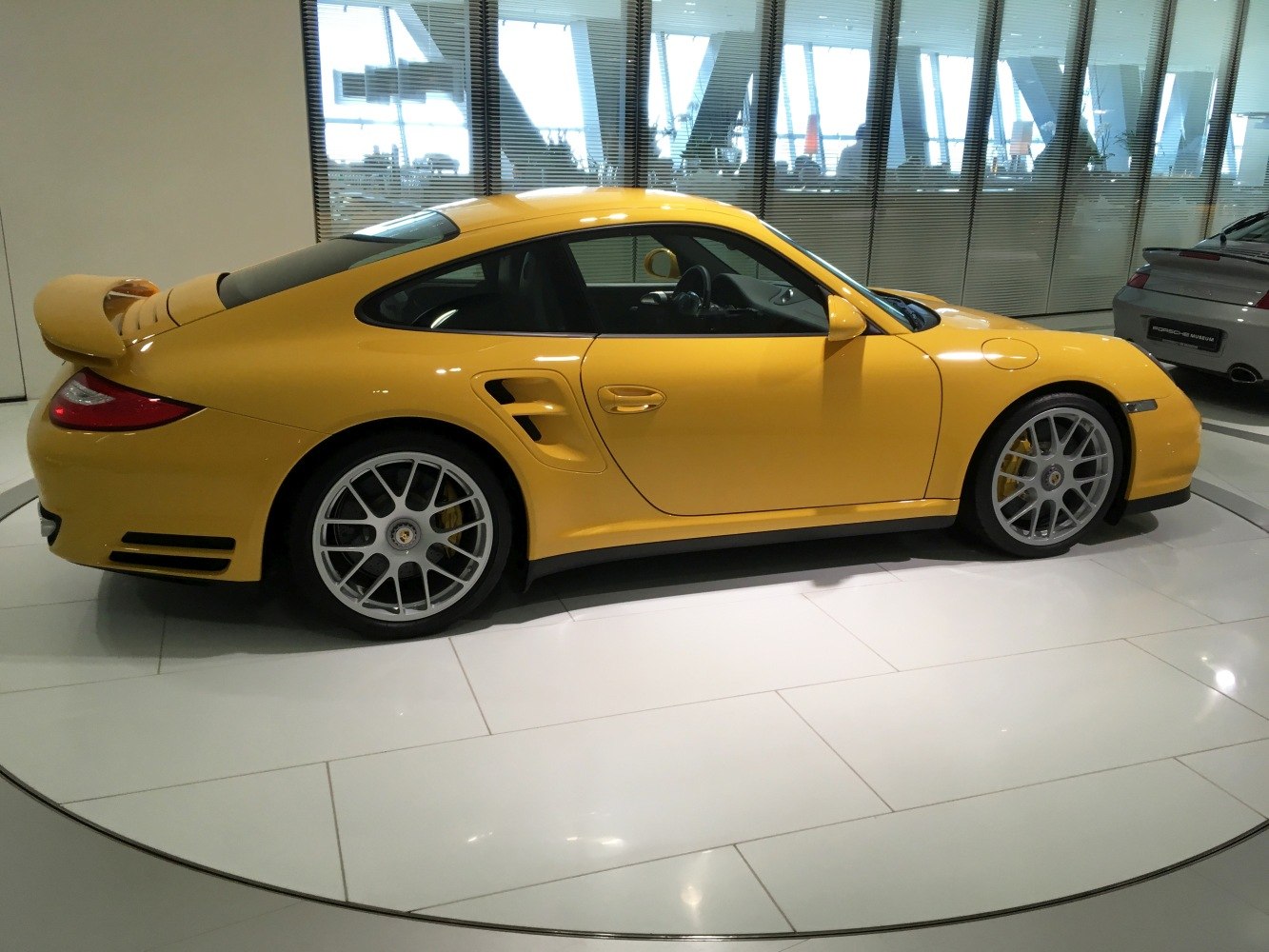 Yellow Porsche 911 (997 facelift) side profile with rear spoiler and alloy wheels