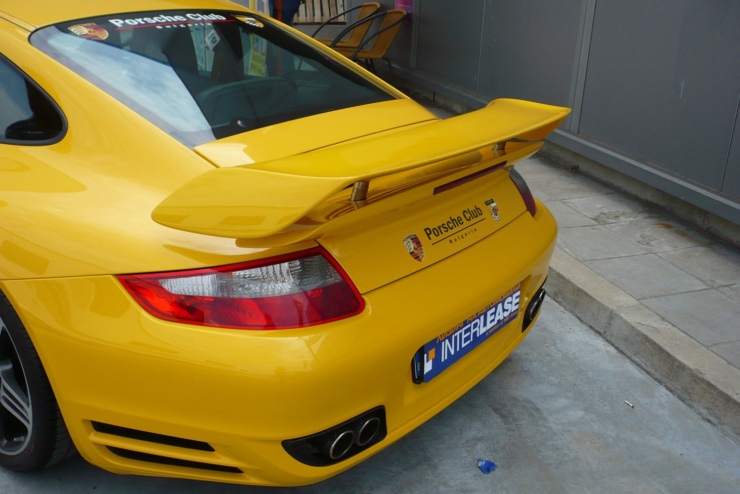 Rear yellow spoiler and quad exhaust of a sports car