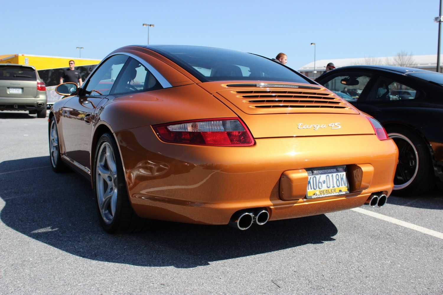 Metallic orange sports coupe rear with quad exhaust and rear grille