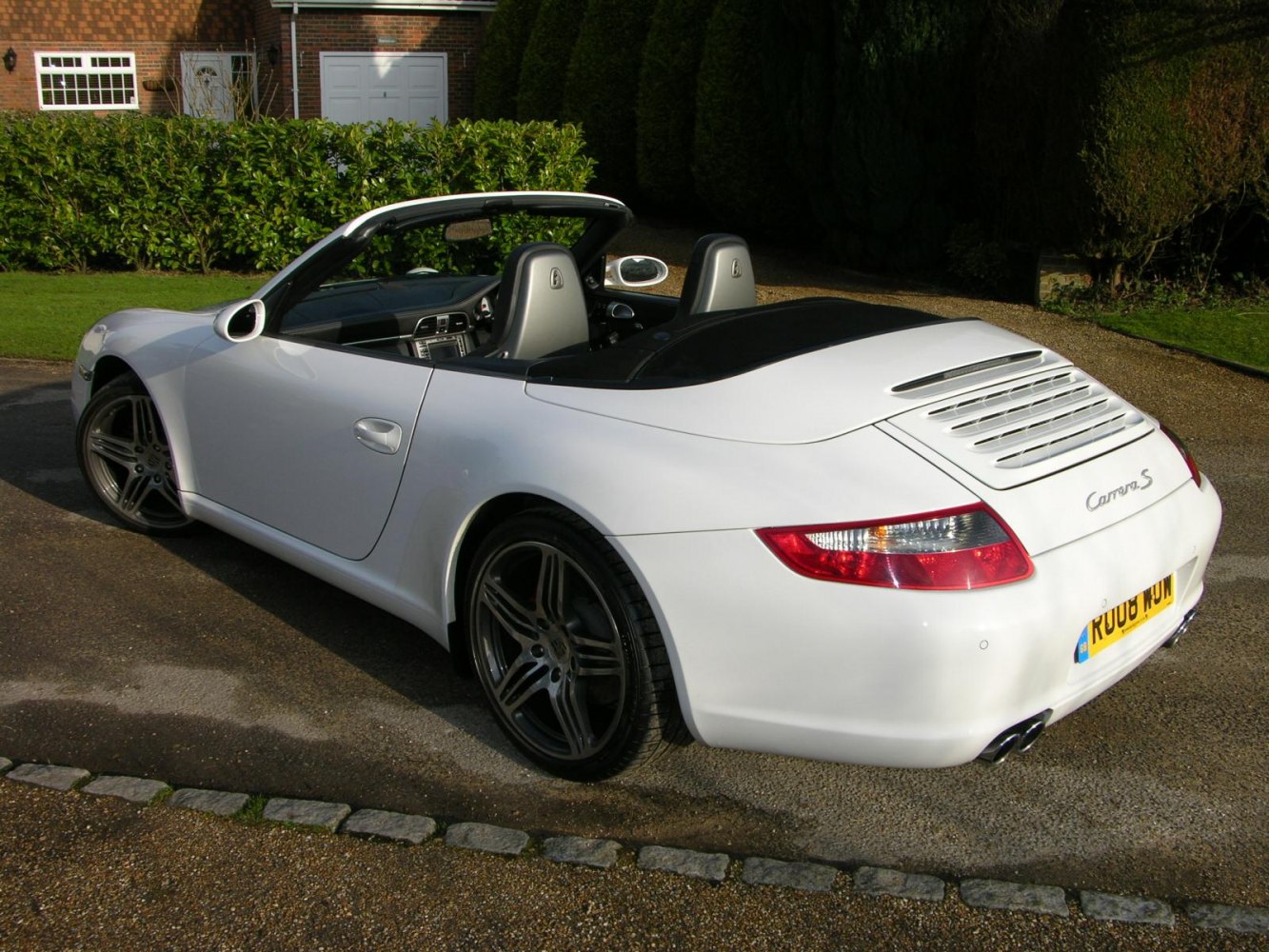White convertible sports car rear and side profile with distinctive rear ventilation slats.