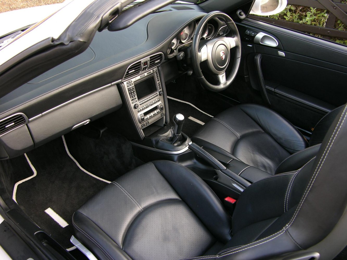Black leather seats and manual transmission inside a convertible sports car.