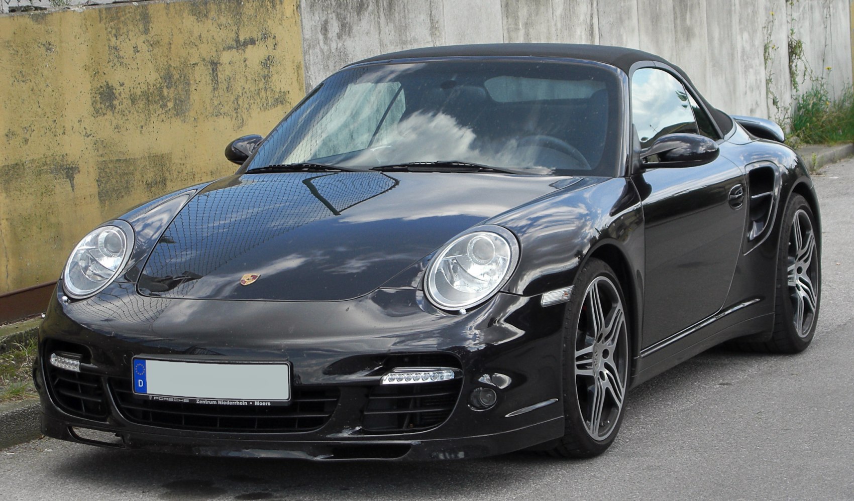 Black convertible sports car with rounded headlights and aerodynamic front design