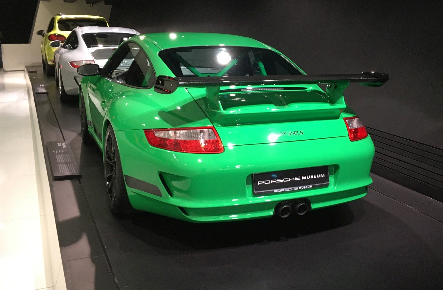 Green sports car rear with large wing spoiler and dual exhausts