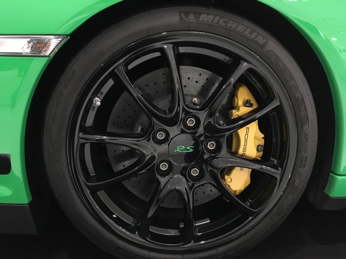 Black alloy wheel with yellow Porsche brake caliper and drilled rotor