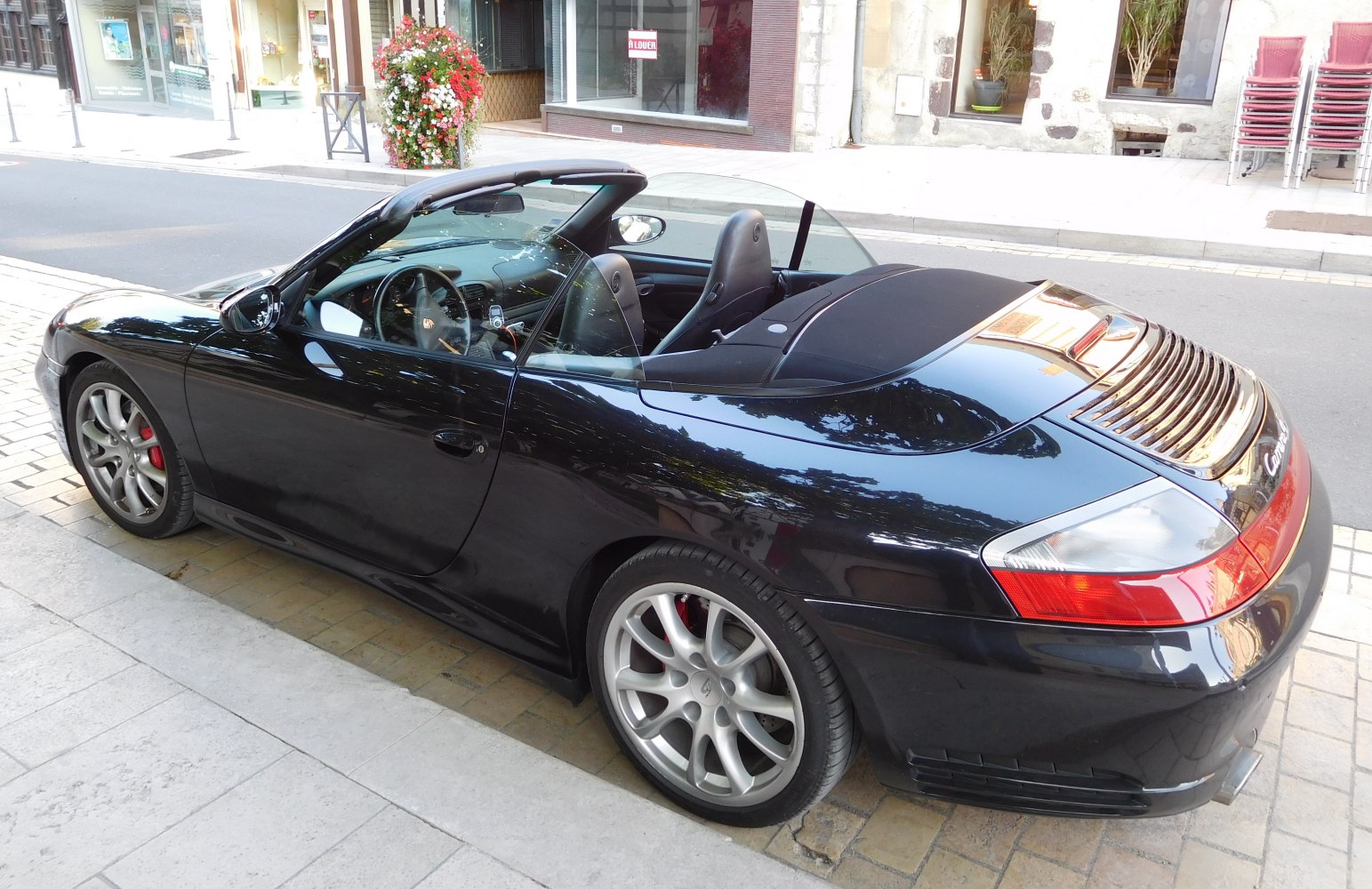 Rear side and interior of a convertible sports car with distinctive rear deck and alloy wheels