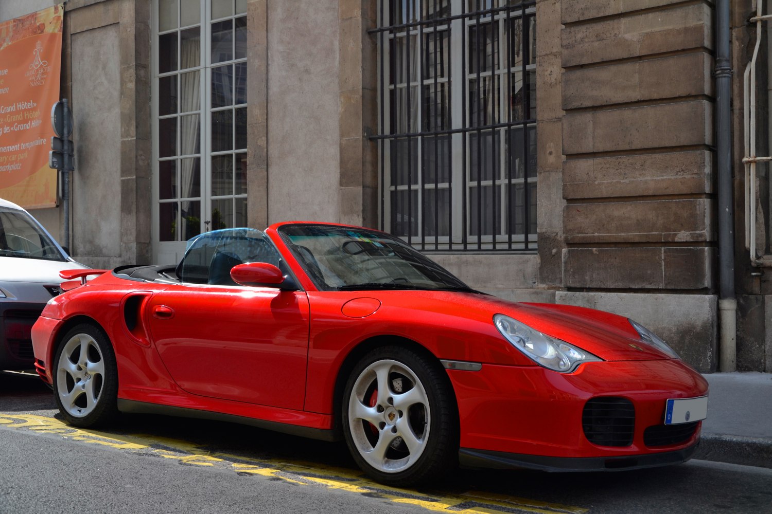 Red convertible sports car with prominent side air intakes and five-spoke wheels