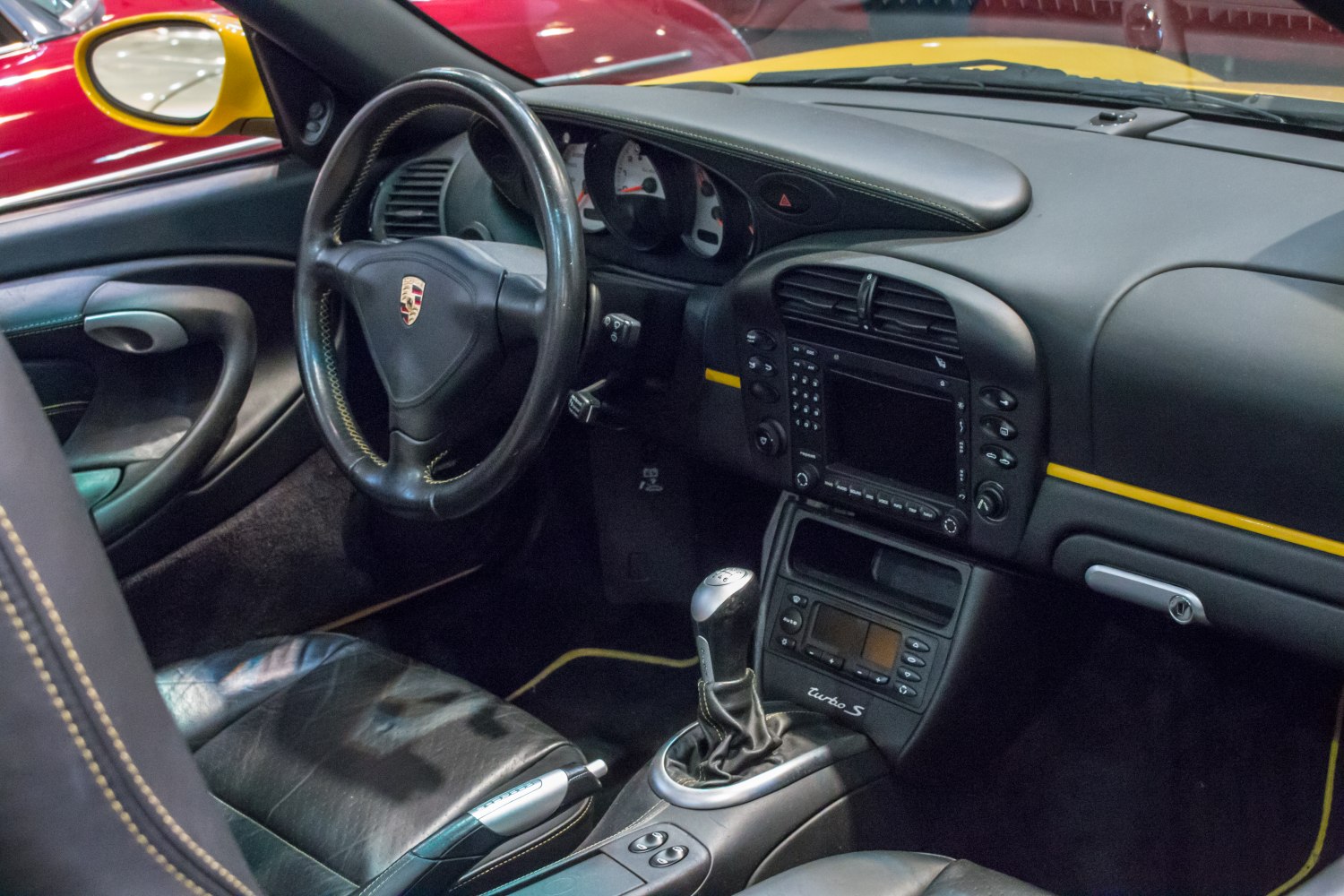 Steering wheel, manual gearshift, black dashboard with controls and Turbo S badge