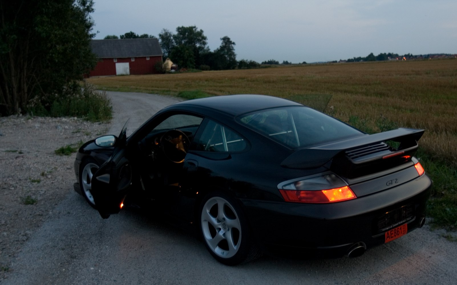 Rear view with open driver door and prominent rear spoiler at dusk