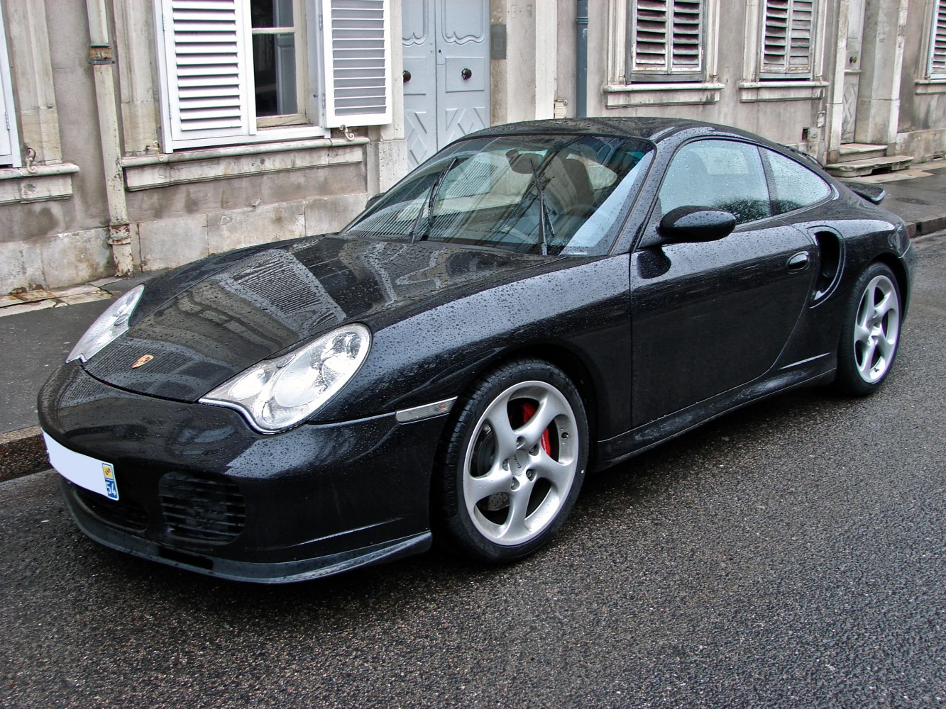 Black sports coupe with smooth lines and distinctive headlights on wet pavement