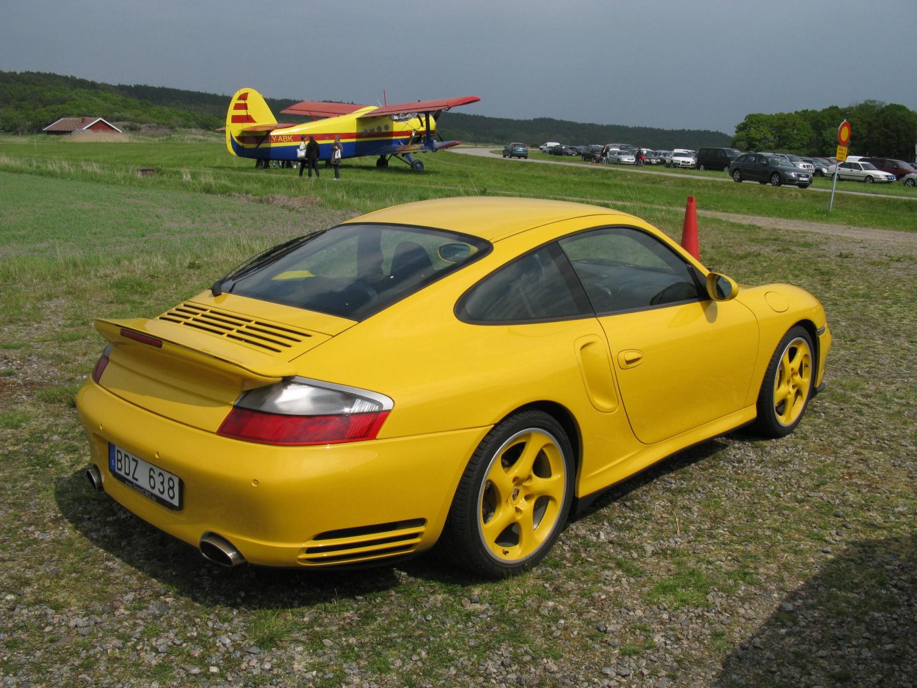 Rear side view of yellow sports coupe with spoiler and matching rims