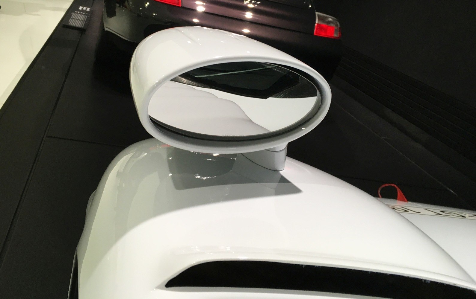White sculpted aerodynamic side mirror on sleek car body