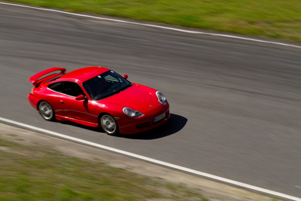 Red sports coupe with rear spoiler racing on a track.
