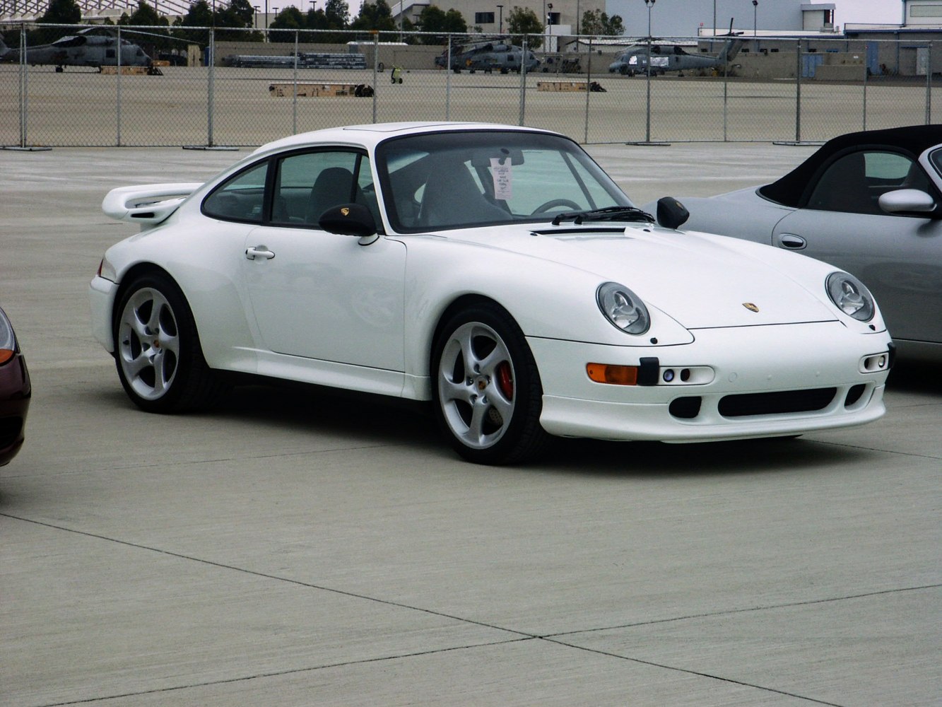 White classic sports car with rounded headlights, rear spoiler, and five-spoke wheels