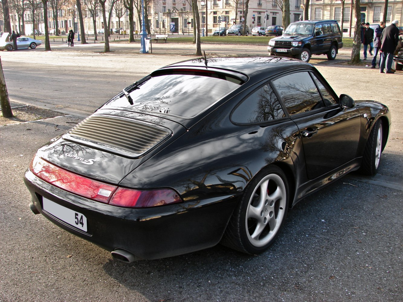 Rear view of black coupe with louvred rear window and curved tail lights
