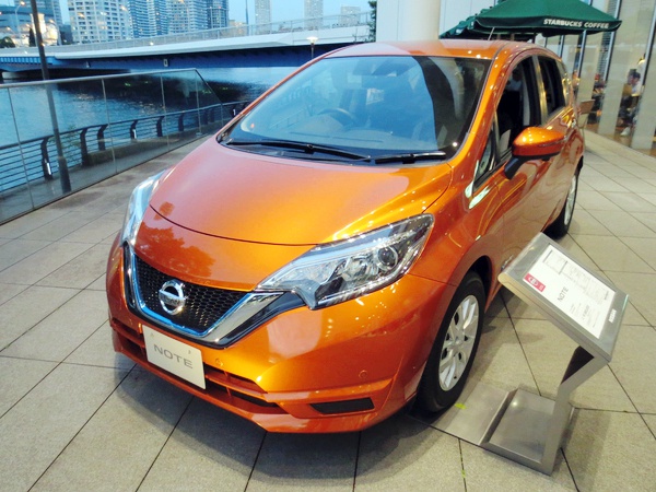 Front and side view of a compact orange hatchback with sharp headlights and modern grille.
