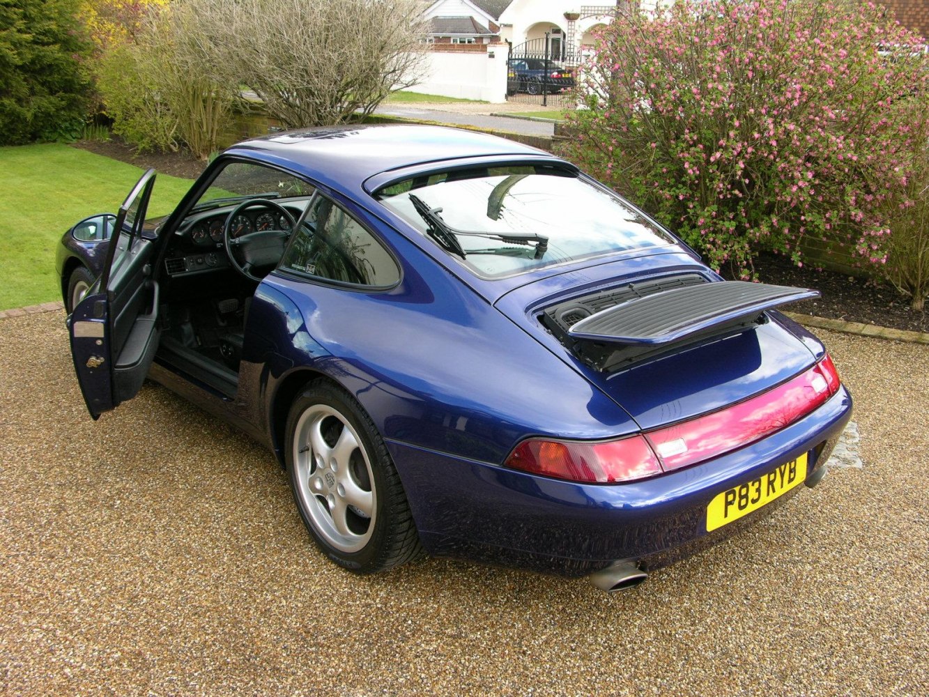 Blue Porsche 911 rear with open door and raised spoiler
