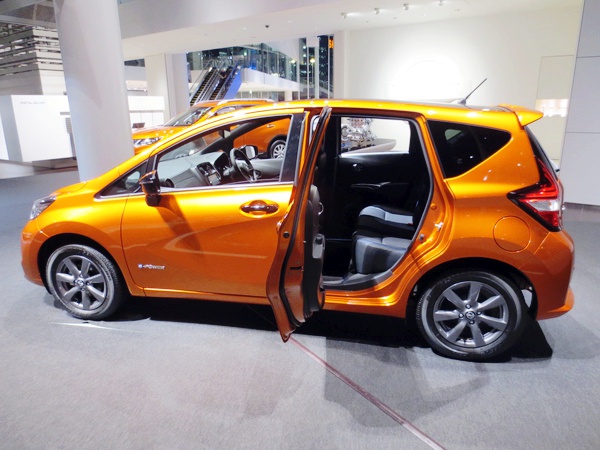 Orange compact hatchback side view with open rear door showing interior