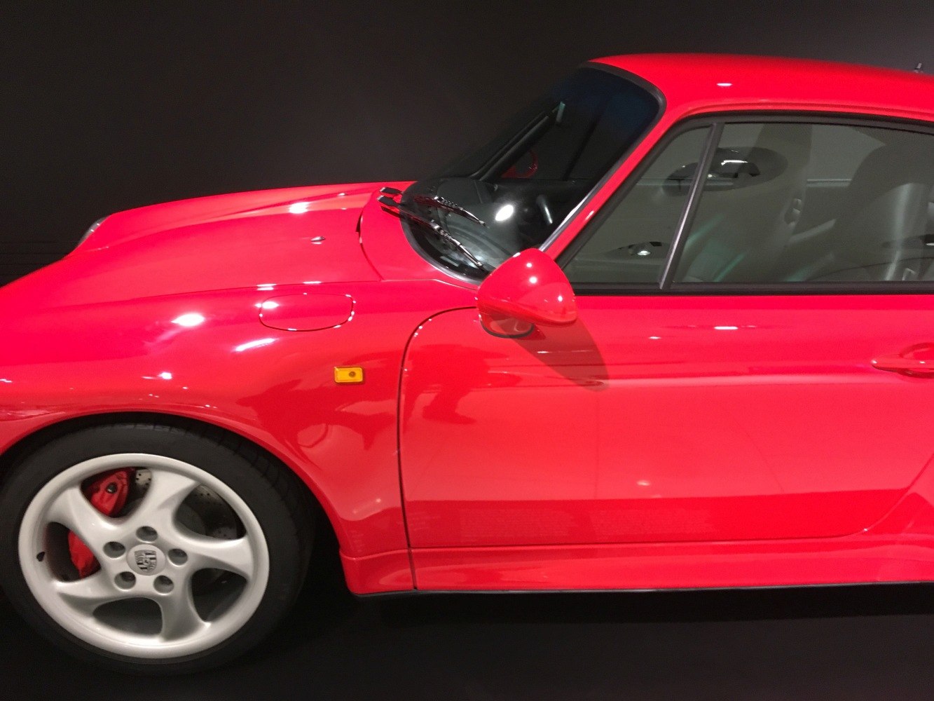 Red sports coupe front side with five-spoke alloy wheel and door details
