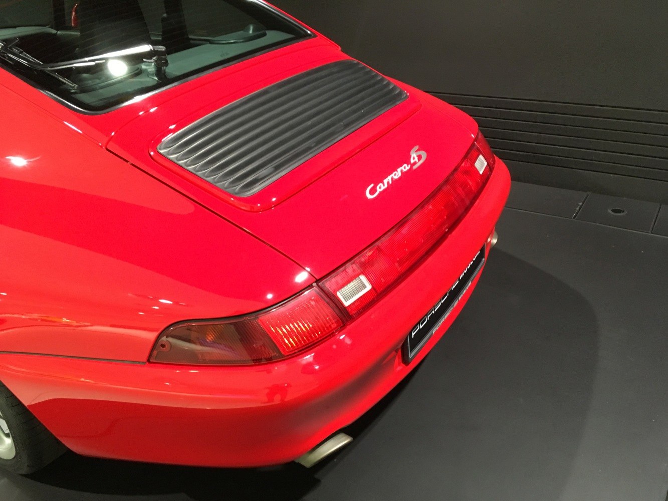 Rear view with iconic taillights and engine grill on a red sports coupe.