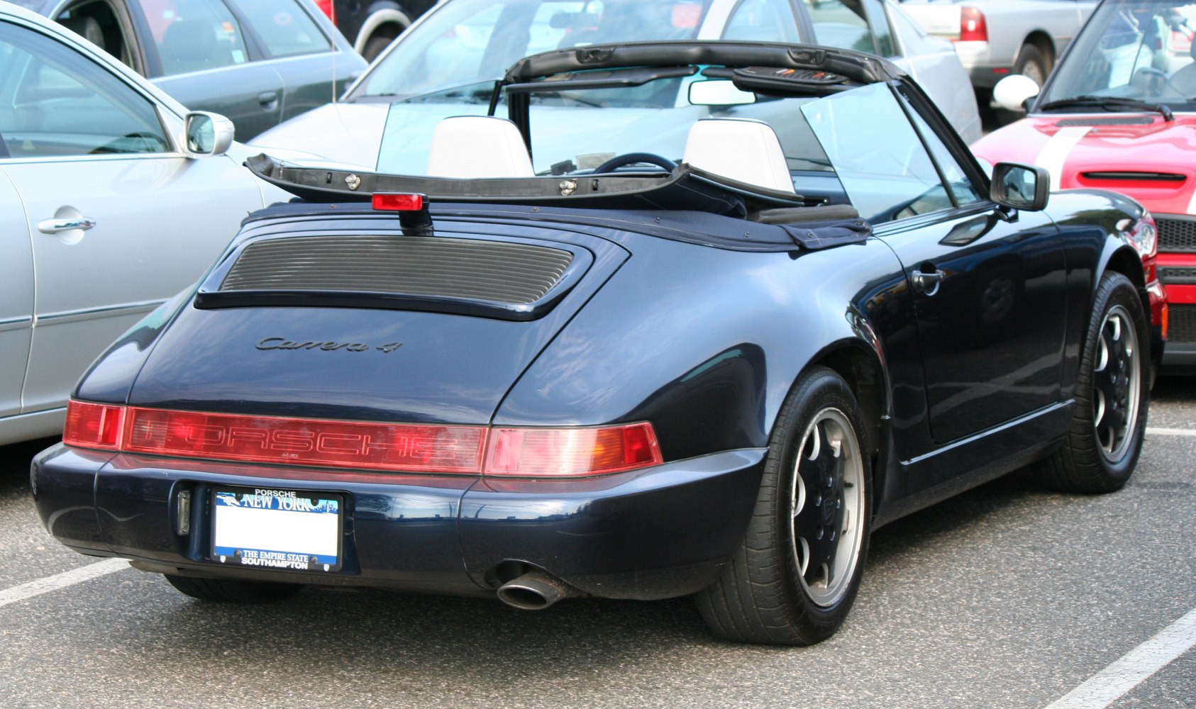 Rear view of a 1990s convertible with full-width red light bar and visible exhaust tip