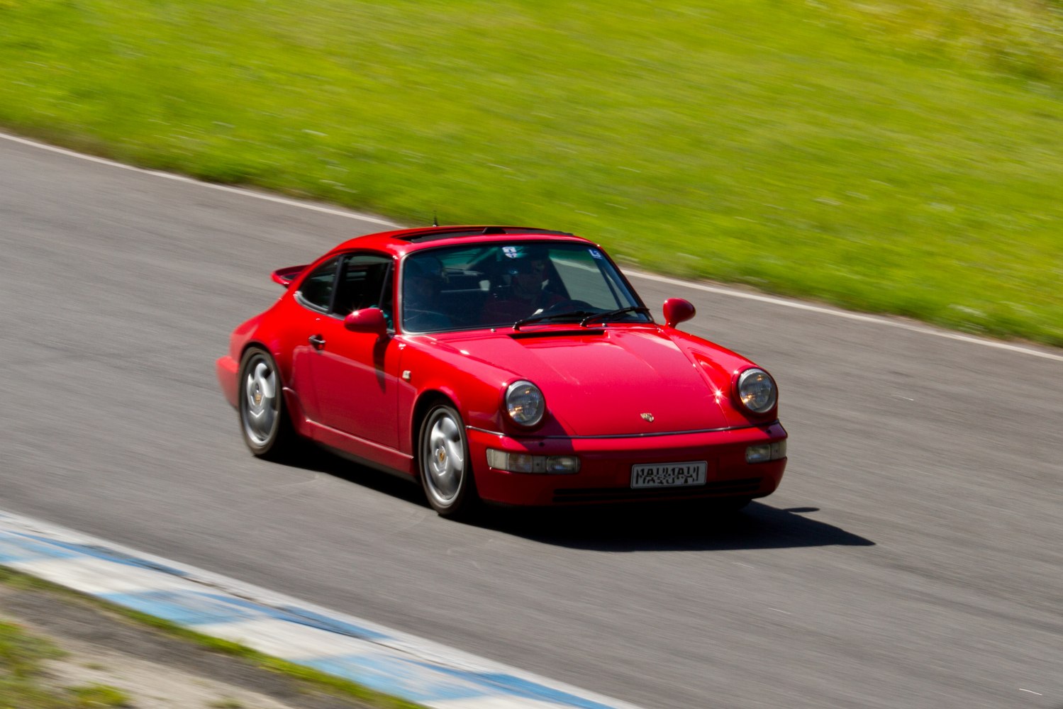 Red classic sports coupe with iconic round headlights on a race track