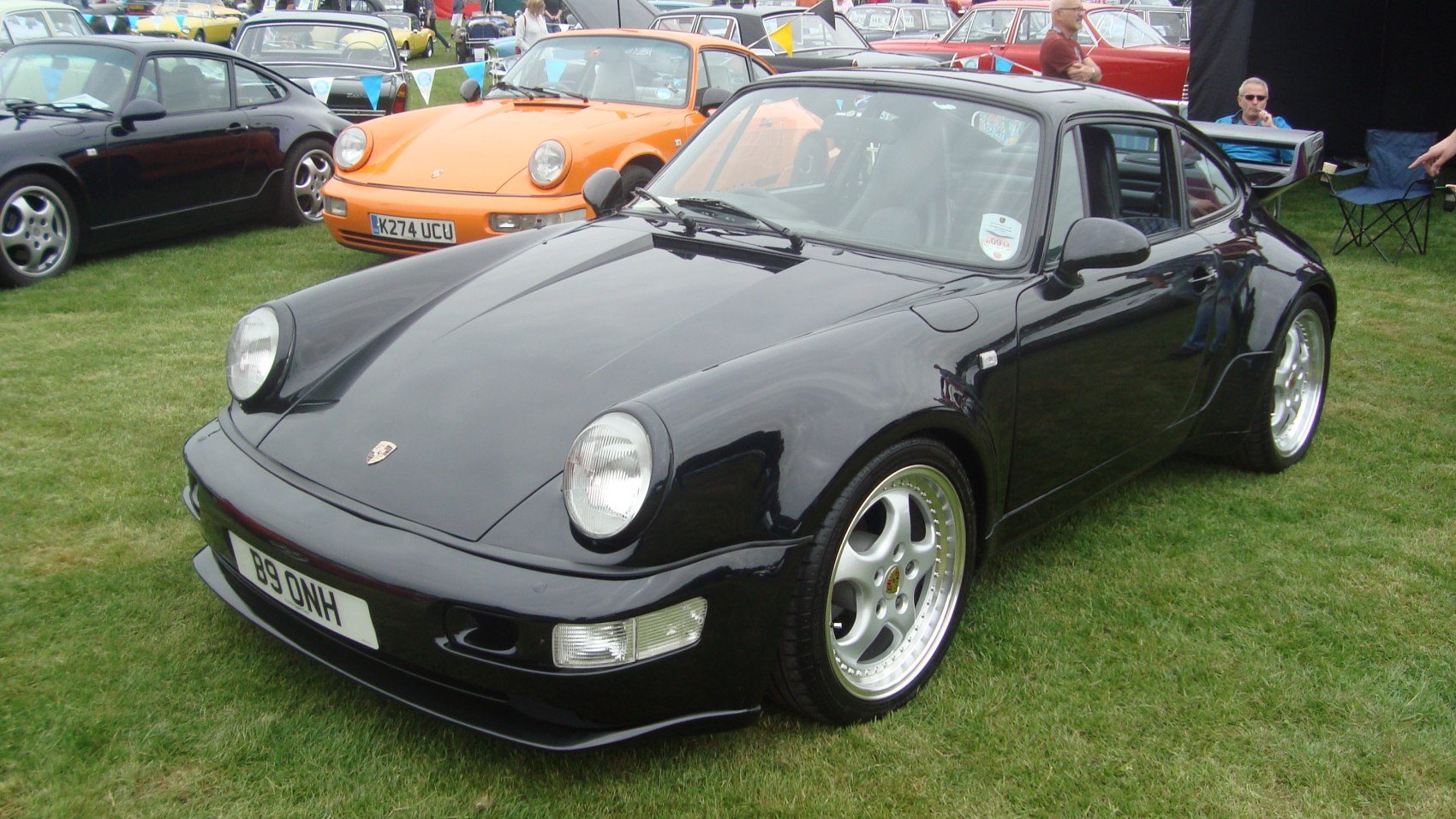 Wide body fenders and five-spoke alloy wheels on a black classic sports coupe.