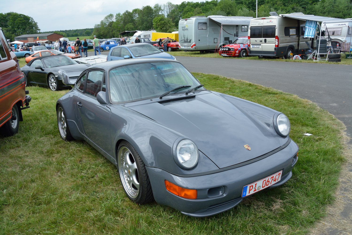 Front and side view of a gray sports car with round headlights and aerodynamic body shape.