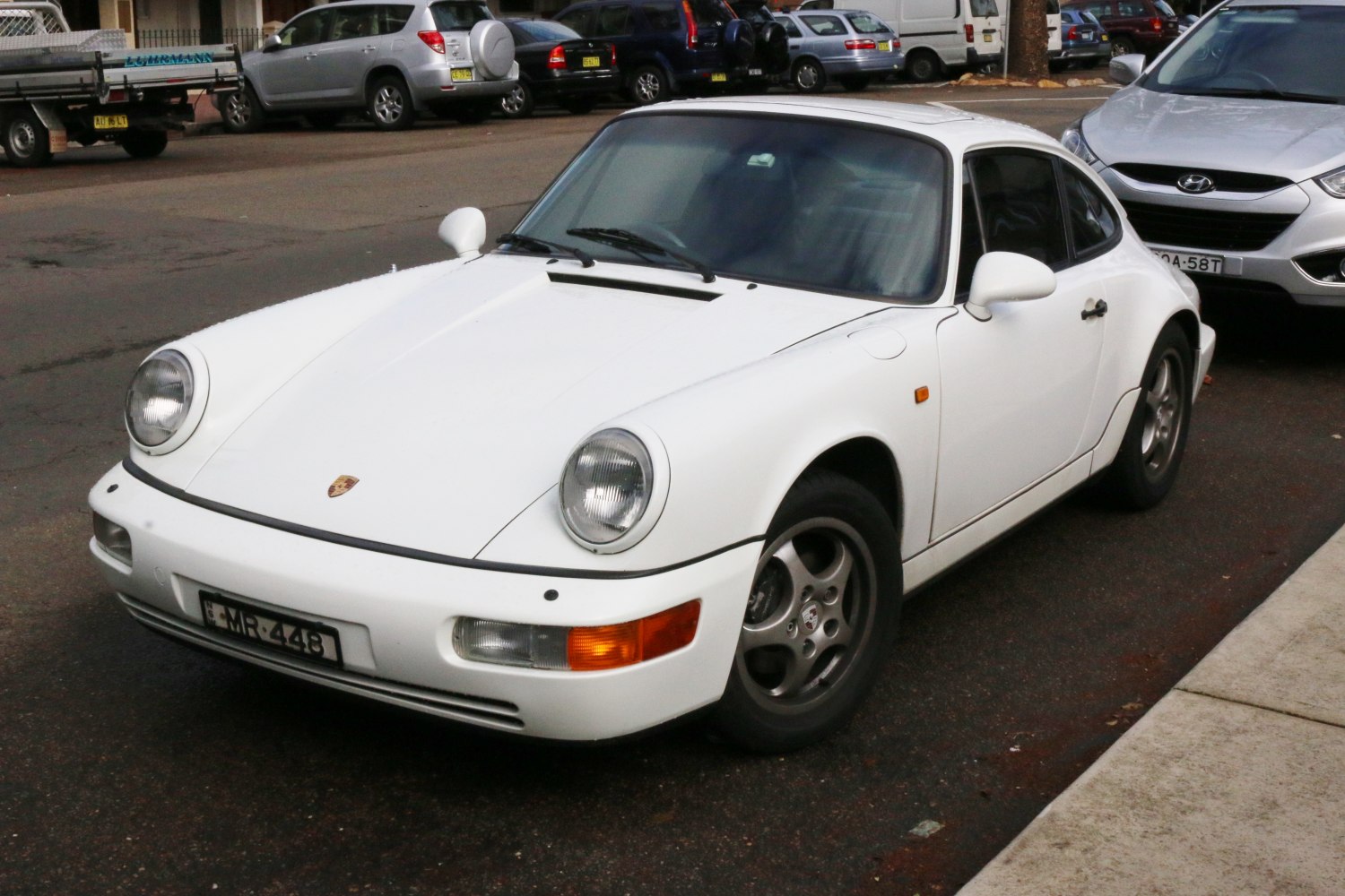 White sports coupe with round headlights and classic front styling.