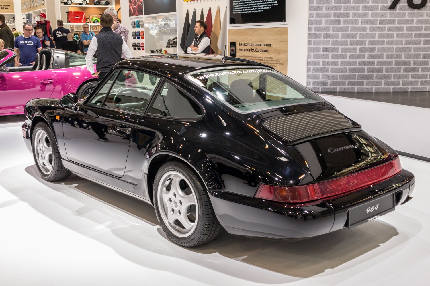 Rear and side view of a black classic sports coupe with smooth curves and distinctive taillights.