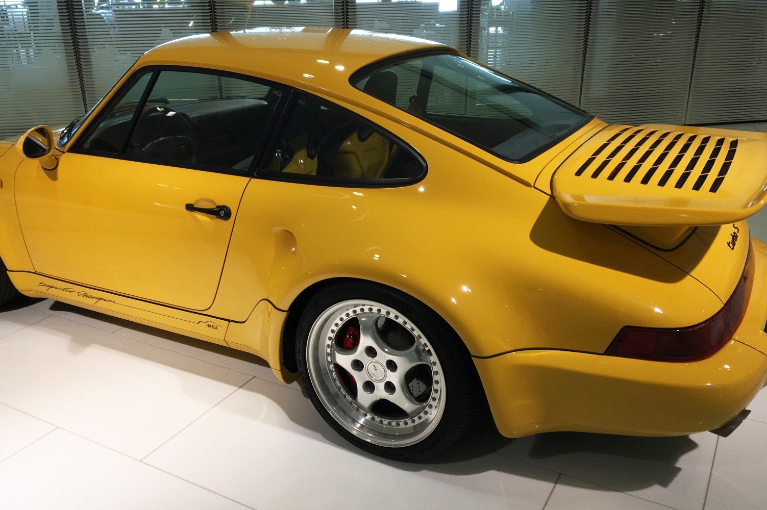 Yellow Porsche rear quarter with spoiler and racing wheels