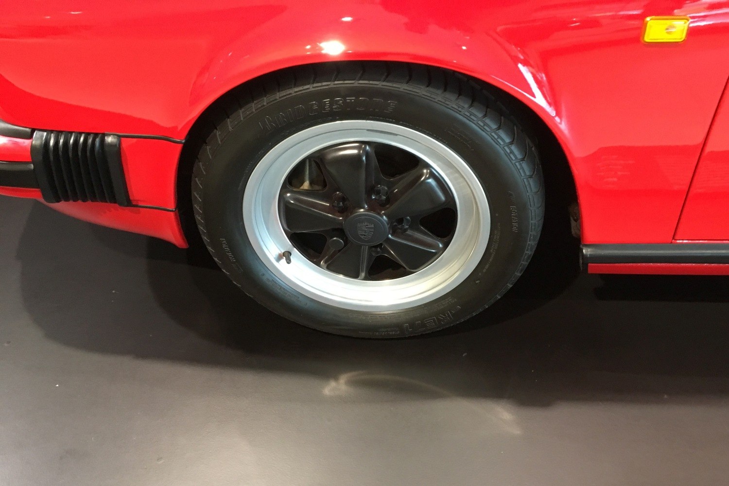 Close-up of classic Fuchs alloy wheel and red car fender