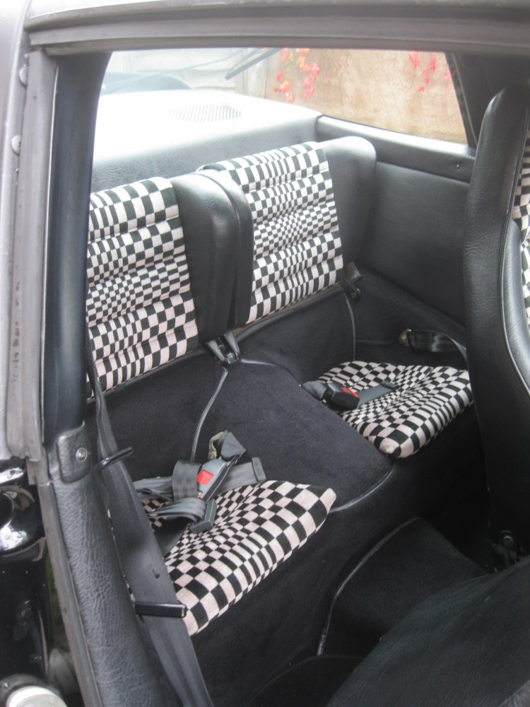 Checkerboard patterned rear seats with seat belts in compact rear cabin