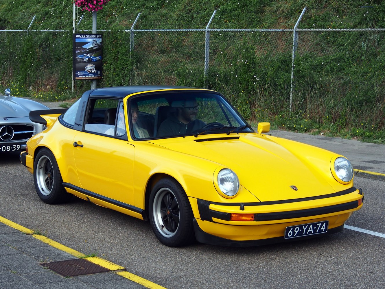 Yellow 1970s sports coupe with black targa roof and round headlights