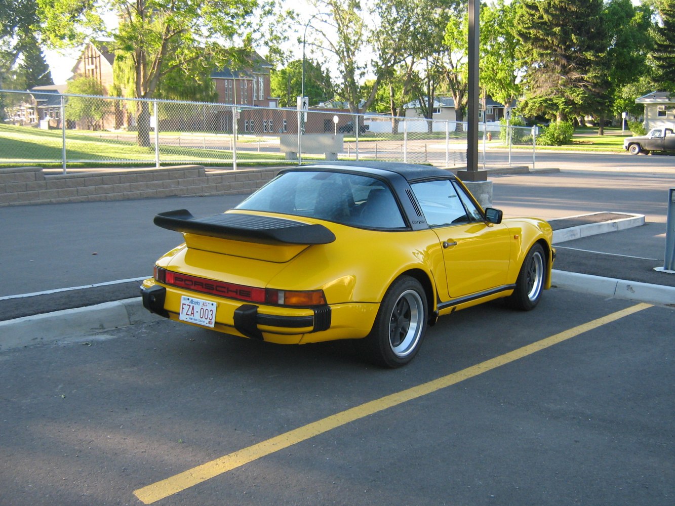Rear view of a yellow Targa with whale tail spoiler and black Targa roof