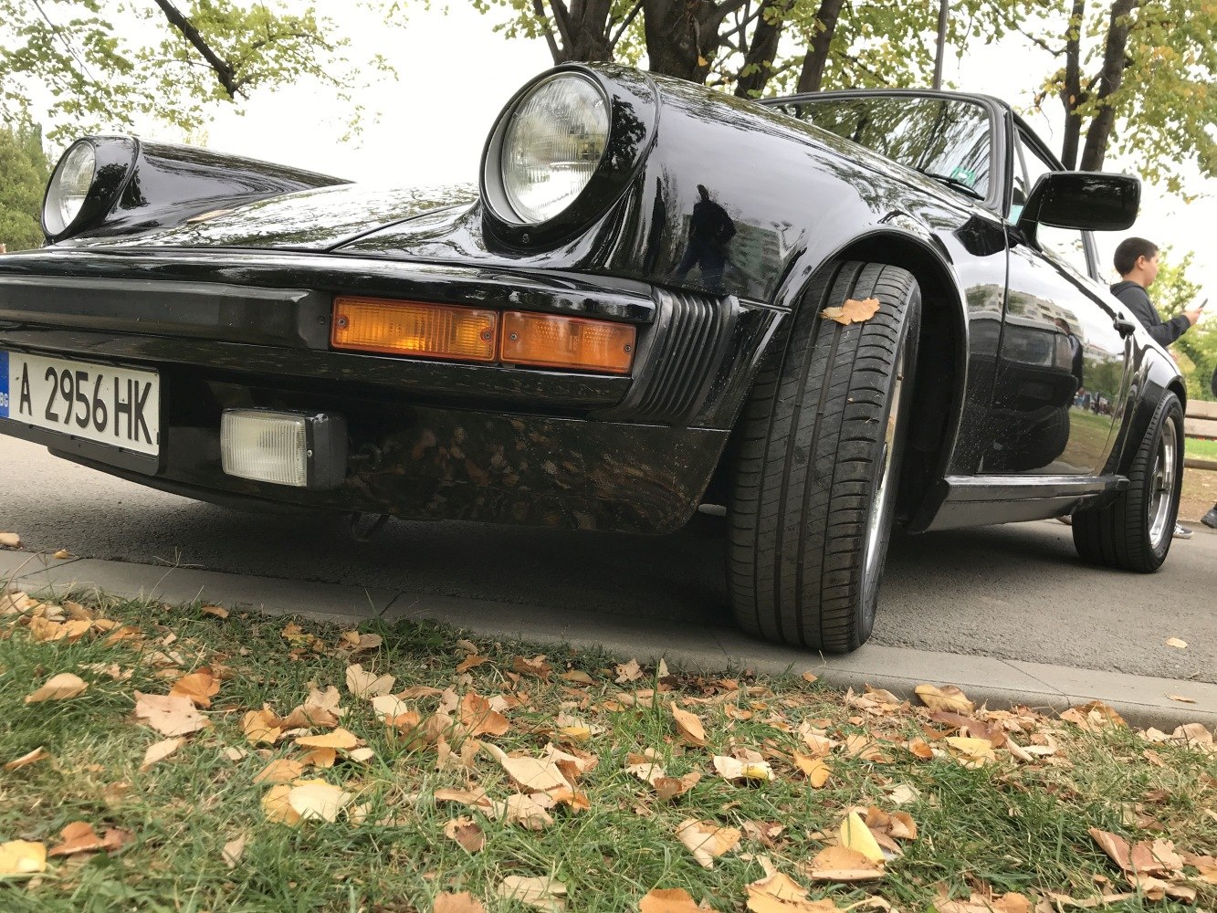 Close-up of round headlights and wide front tires on classic car.