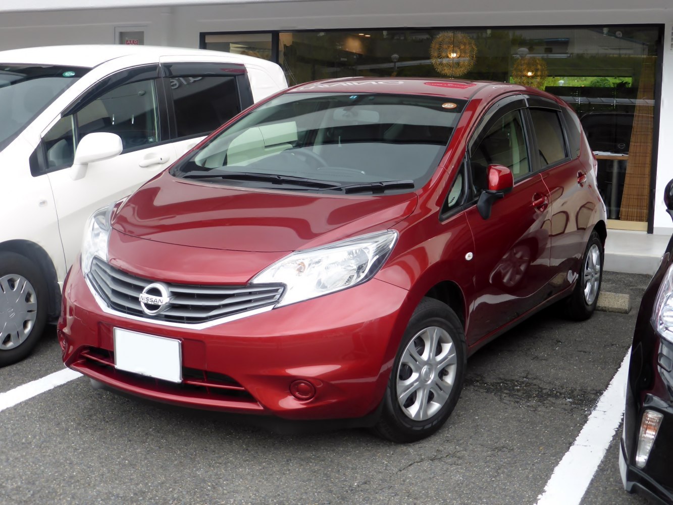 Front side view of red compact hatchback with prominent grille and headlights