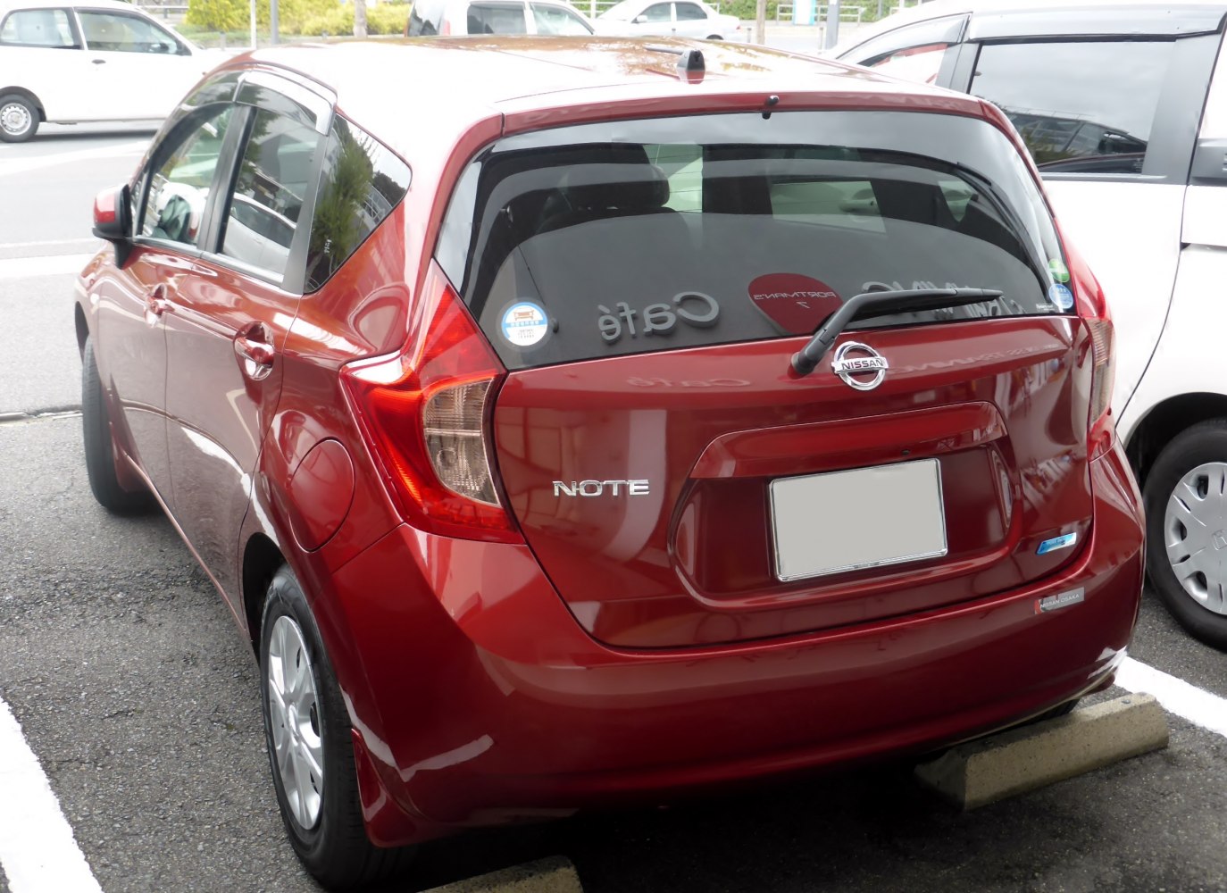 Red compact hatchback rear with distinctive tail lights and rear windshield wiper