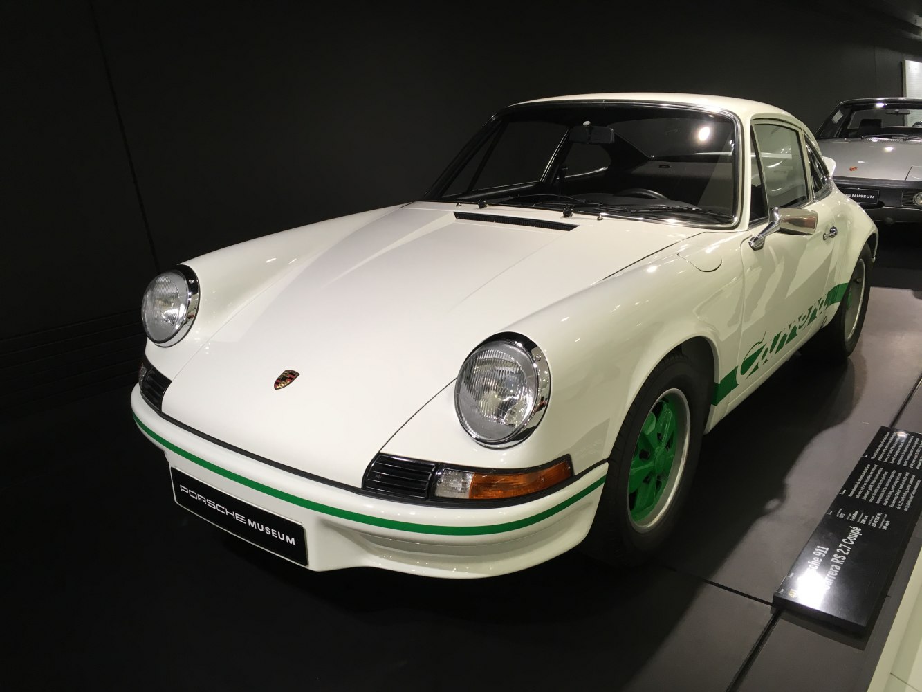 White vintage car with round headlights and green accents on rims and stripes